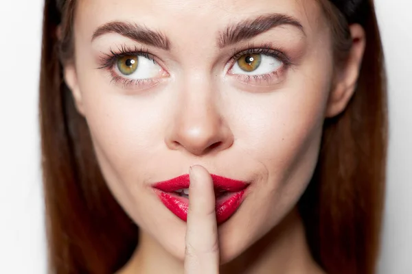Mujer con labios rojos sosteniendo un dedo cerca de la mirada lateral de la cara — Foto de Stock