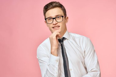 Beyaz gömlekli, kravatlı, gözlüklü, kendine güvenen, resmi pembe arka planlı bir iş adamı.