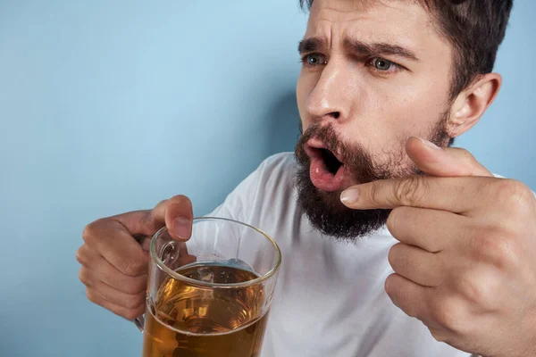 Homem alegre em uma camiseta branca com uma caneca de cerveja bebido fundo azul — Fotografia de Stock