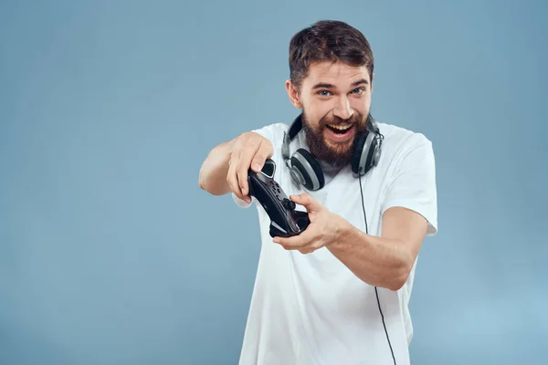 Een man met een controller in zijn handen koptelefoon games hobby vrijetijdsbesteding technologie levensstijl blauwe achtergrond — Stockfoto