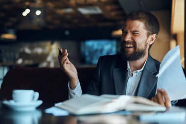 Bir kafede masada oturan bir iş adamı resmi kahve fincanında çalışır. 