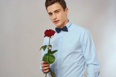 Kırmızı güllü, mavi gömlekli, boynunda papyon olan romantik bir adam.