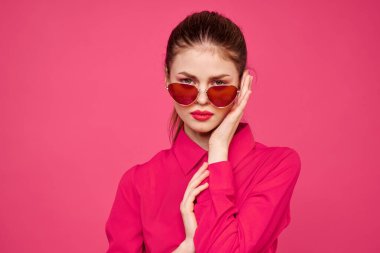 Pembe gömlekli ve kahverengi gözlüklü kadın kırpılmış görünüm modeli duyguları el hareketleriyle resim yapıyor.