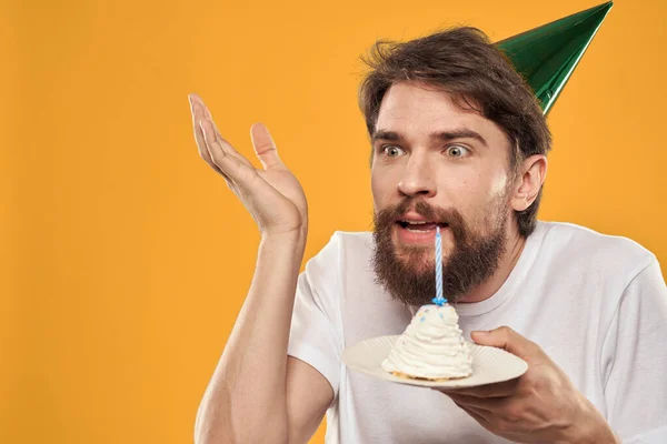 Un hombre con gorra en un cumpleaños de vacaciones de fondo amarillo — Foto de Stock