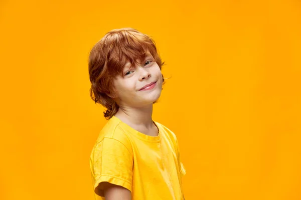 Niño feliz con el pelo rojo sonriendo a la cámara en el fondo aislado recortado vista —  Fotos de Stock