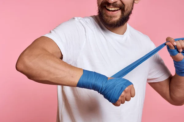 Sportos férfi egy fehér póló boksz kötszerek a kezét egy edzés életmód rózsaszín háttér — Stock Fotó
