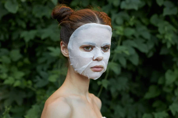 Nice woman anti-aging mask bare shoulders leaves in the background