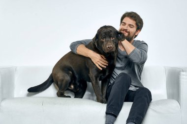 Kanepede evcil köpeği olan bir adam. Arkadaşlarıyla eğleniyor.