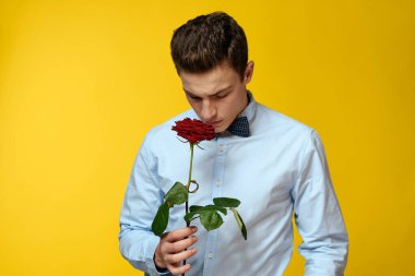 Gömlekli ve papyonlu bir beyefendi boynunda sarı arka planda kırmızı gül