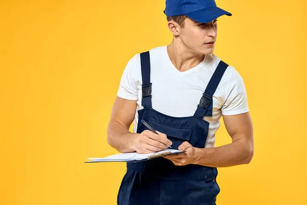 Çalışan üniformalı bir adam servis servisi sarı arka planını sunuyor. — Stok fotoğraf