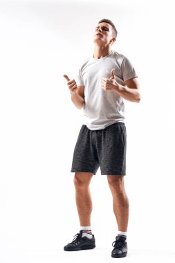 Hafif bir geçmişi olan atletik bir adam tam boy ve koşu şortu spor ayakkabısı tişörtü giyiyor.