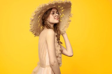 Sarı arka planda saman şapkalı portre kadın. Yazlık elbise mankeni romantizmi.
