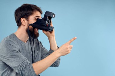 Profesyonel bir kamerayla elinde profesyonel bir fotoğrafçı hobi olarak yaratıcılığın mavi arka planına yaklaşıyor.