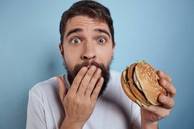 Duygusal adam hamburgeri fast food diyeti yakın plan mavi arka plan