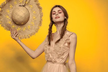 Sarı arkaplan duygularıyla elinde hasır şapkalı bir kadın... 