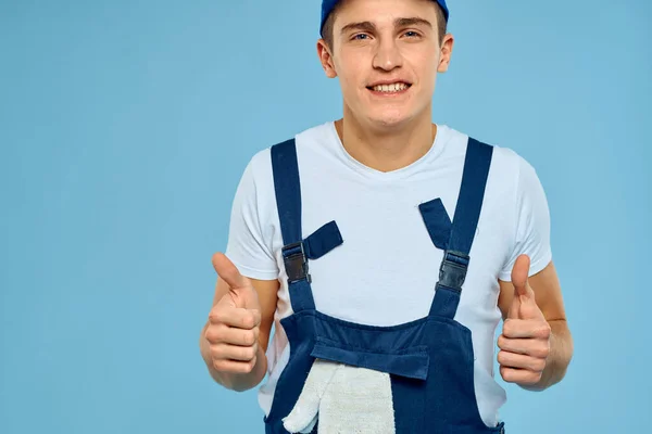 Hombre trabajador en uniforme de guantes cargador prestación de servicio fondo azul — Foto de Stock