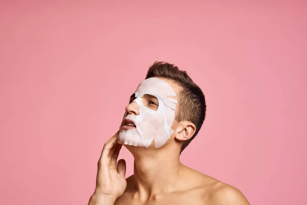 Homem com máscara de limpeza contra pontos pretos em seu rosto no fundo rosa vista cortada e mãos perto do rosto — Fotografia de Stock