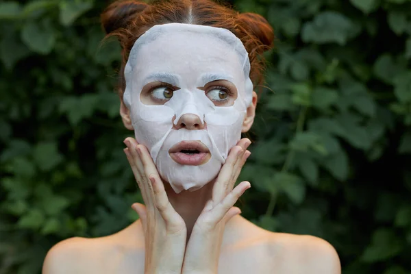 Belle fille rajeunissement de masque cosmétique Surpris de toucher votre visage avec vos mains buissons en arrière-plan — Photo