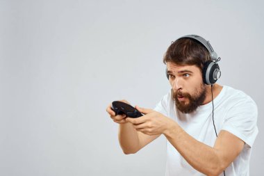 Gamepad 'li kulaklıklı bir adam hobi hayatı tarzı hafif arka planda oynuyor.