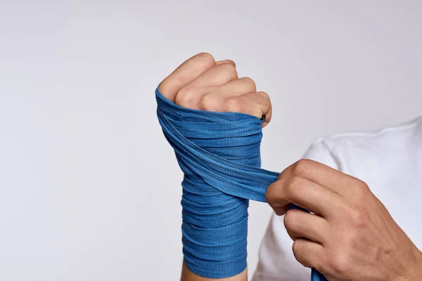 A man ties his hand with boxing bandages in a white T-shirt — Stock Photo, Image