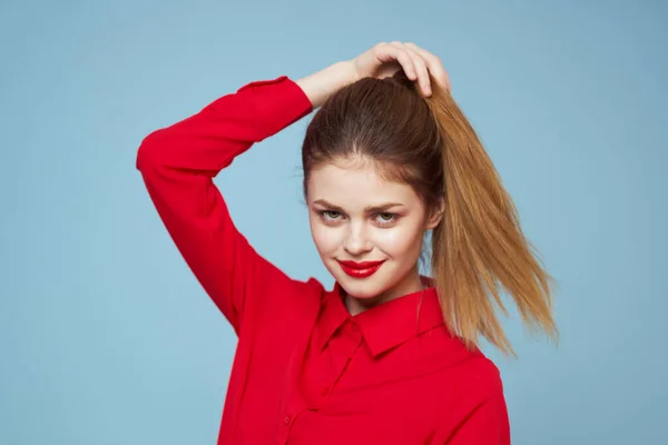 Happy girl in bright clothes on a blue background touches the hair on her head with her hands — Stock Photo, Image