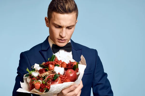 Romantische man met een boeket bloemen en in een strikje op een blauwe achtergrond bijgesneden uitzicht — Stockfoto