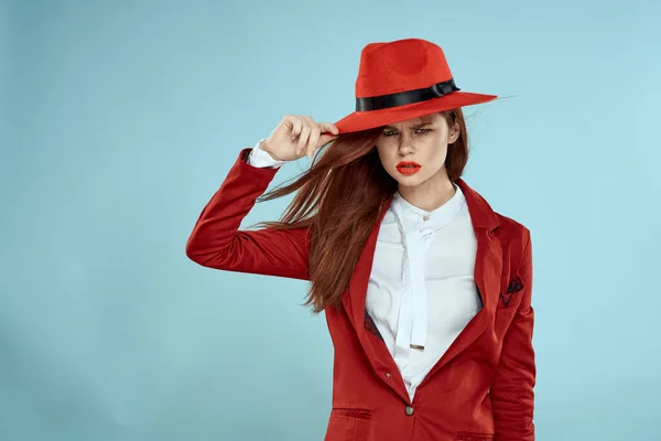 Vacker kvinna i röd hatt jacka röda läppar långt hår charm blå bakgrund — Stockfoto