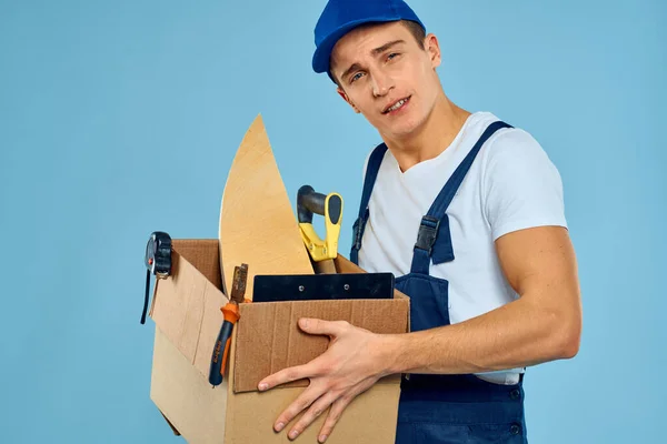 Working man in uniform box with tools dostawa ładowarki niebieski tło — Zdjęcie stockowe