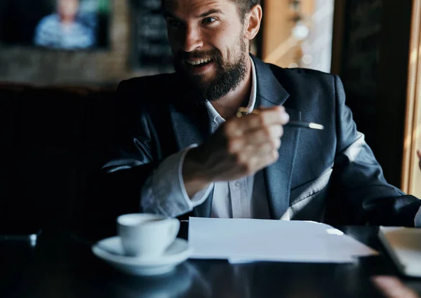 Homem de negócios sentado a uma mesa em um café documentos de trabalho copo de café oficial — Fotografia de Stock