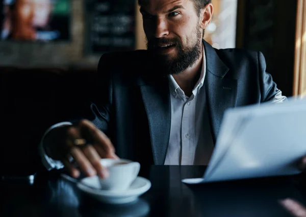 Homem de negócios sentado a uma mesa em um café documentos de trabalho copo de café oficial — Fotografia de Stock