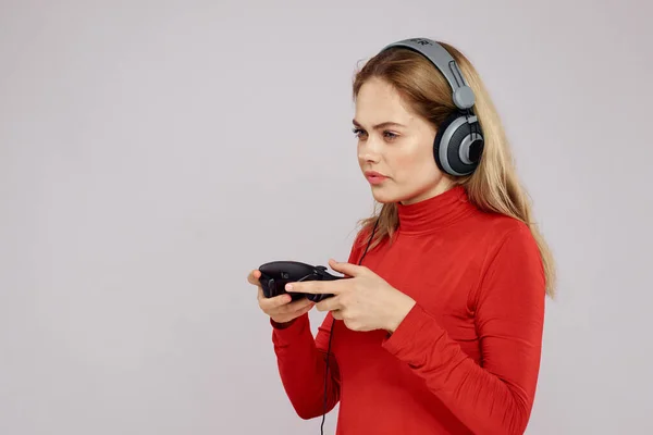 Frau mit Kopfhörer Joystick in den Händen Spielen Spaß Freizeit Lifestyle Unterhaltung rotes Hemd grauer Hintergrund — Stockfoto