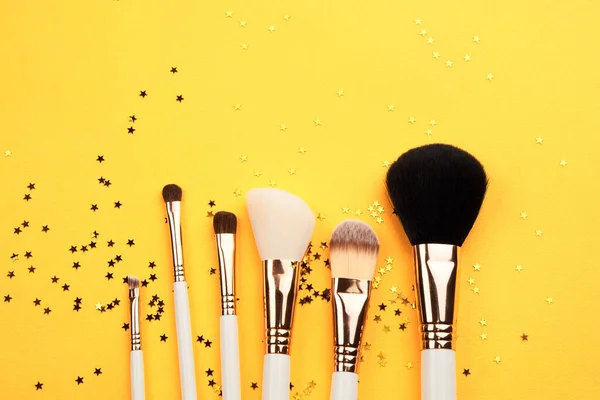 Pinceles de maquillaje de diferentes tamaños sobre fondo amarillo recortado vista Copiar espacio —  Fotos de Stock