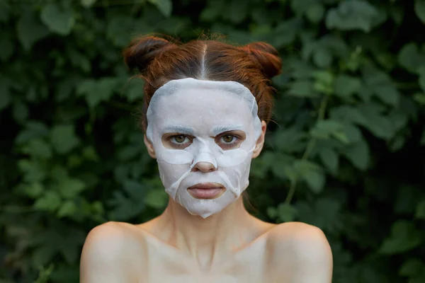 Belle femme masque facial Vue frontale peau propre cosmétologie buissons en arrière-plan — Photo