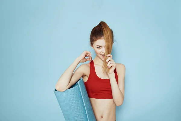 Sportieve vrouw in rode tank top mat voor workout oefeningen lifestyle blauwe achtergrond — Stockfoto