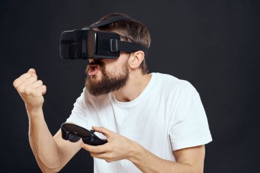 Sanal gerçeklik gözlüğü takan ve el teknolojisi oyunlarında oyun alanı olan bir adam. Boş zamanlarında karanlık arka plan.