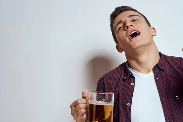 Fylld man med en mugg öl semester alkohol livsstil i en röd skjorta känslor ljus bakgrund — Stockfoto