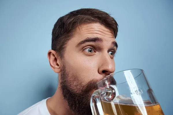 Homme joyeux dans un T-shirt blanc avec une tasse de bière fond bleu ivre — Photo