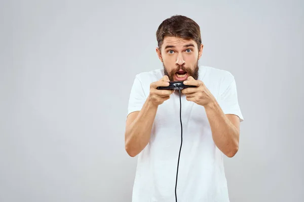 Ein Mann mit einem Gamepad in der Hand spielt Spiele Freizeit Lifestyletechnologie weißes T-Shirt heller Hintergrund — Stockfoto