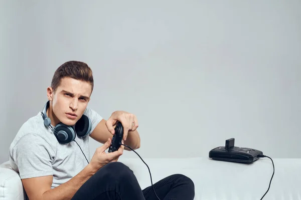 Ένας άνδρας κάθεται στον καναπέ με ακουστικά ένα βιντεοπαιχνίδι set-top διασκεδαστικό κουτί ψυχαγωγίας — Φωτογραφία Αρχείου