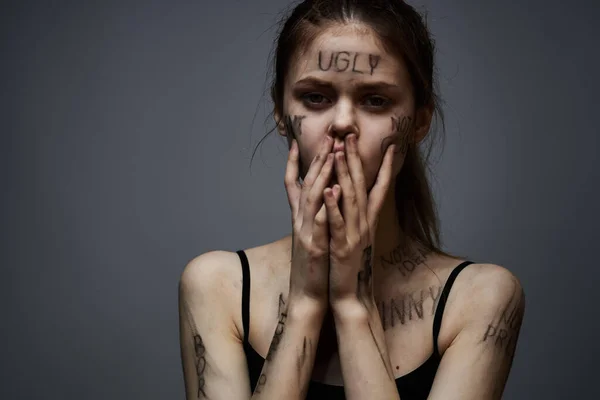 Donna sconvolta con scrittura offensiva sul suo corpo su sfondo grigio toccarsi con le mani ritagliato vista — Foto Stock
