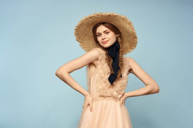 Mavi arka planda pembe elbiseli bir kız elleriyle romantik modeller yapıyor.