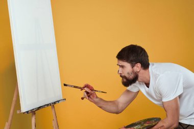 Erkek sanatçı palet resim sehpası hobi yaşam tarzı yaratıcılık sarı arka plan