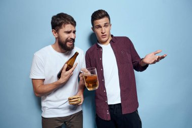İki neşeli sarhoş arkadaş mavi bir arka planda bira içiyorlar.