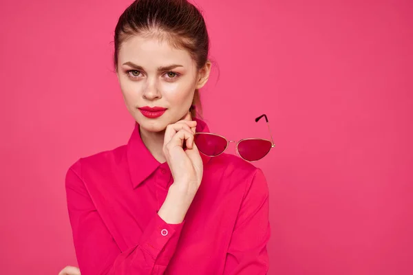 Fashion woman in pink shirt with glasses in hands on isolated background cropped view — Stock Photo, Image