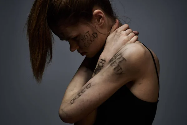 Αναστατωμένη γυναίκα με προσβλητικό γράψιμο στο σώμα της σε γκρι φόντο αγγίζοντας τον εαυτό της με τα χέρια περικοπεί άποψη — Φωτογραφία Αρχείου