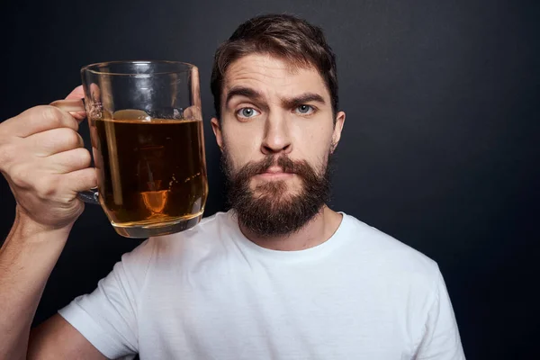 Homme avec une tasse de bière dans un t-shirt blanc émotions style de vie ivre sur un fond sombre isolé — Photo