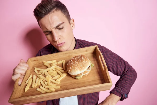 Mann mit Fast Food essen Hamburger Pommes rosa Hintergrund — Stockfoto