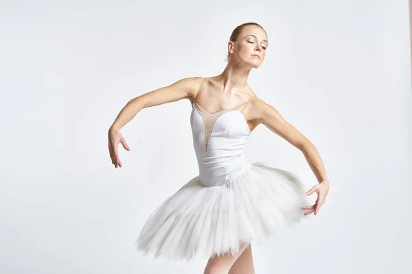 Bailarina em um tutu branco realizando dança exercício flexibilidade luz fundo — Fotografia de Stock
