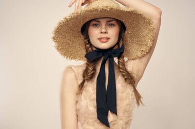 Siyah kurdeleli, saman şapkalı ve bej arka planda kırpılmış manzaralı şirin bir kız.