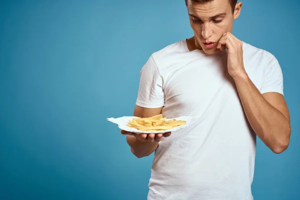 Hombre con patatas fritas en placa de cartón calorías comida rápida azul fondo adolescente modelo recortado ver — Foto de Stock